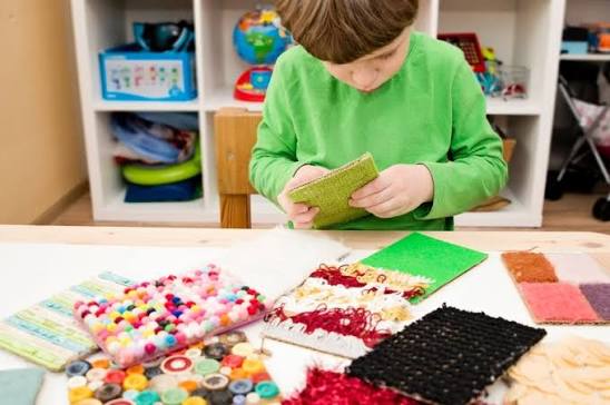 Niño explorando materiales sensoriales de distintas texturas sobre una mesa
