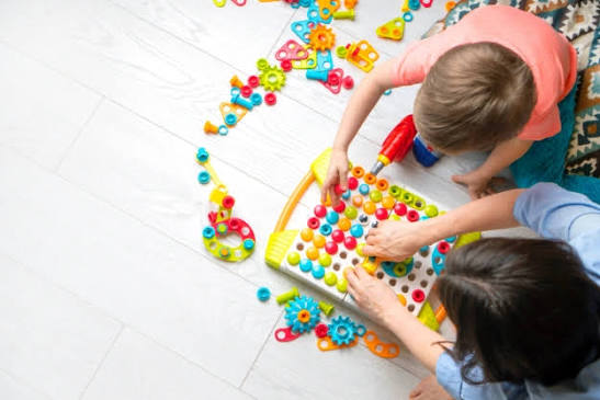 Terapeuta y niño trabajando juntos con un juego de encastres en el piso